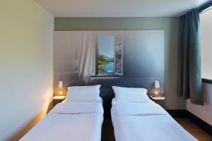 Un pat sau paturi într-o cameră la B&B HOTEL Pau Zénith