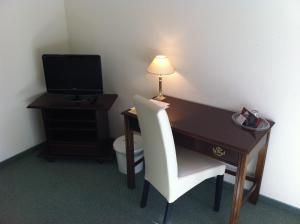 a desk with a white chair and a television in a room at Pension Seba in Grevesmühlen