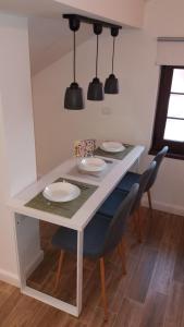 mesa de comedor con sillas, platos y luces en Enjoy Apartment, en Timisoara