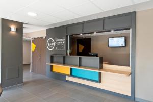 an office lobby with a reception desk and a tv at B&B HOTEL Pau Zénith in Pau +32 photos