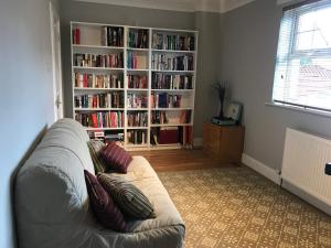 a living room with a couch and a book shelf with books at The Neuk in Uphall
