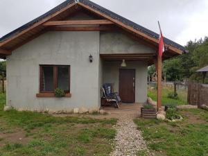 une petite maison blanche avec une véranda et un drapeau dans l'établissement Chatki u Patki, à Łebieniec