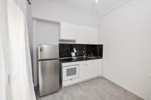 uma cozinha com armários brancos e um frigorífico de aço inoxidável em Modern, comfortable apartment, in the heart of the city em Lárissa