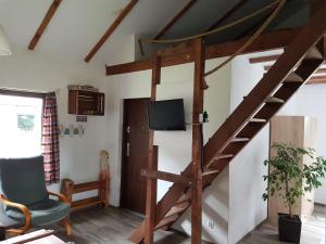 uma sala de estar com uma escada de madeira e uma televisão em Chatki u Patki em Łebieniec