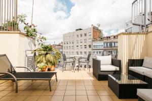 einen Balkon mit Stühlen und Tischen auf einem Gebäude in der Unterkunft Wello Apartments in Barcelona