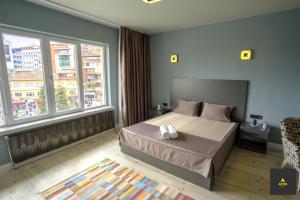 a bedroom with a bed and two windows at Atos Otel in Eskisehir
