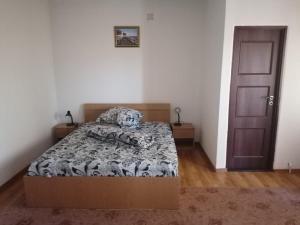 1 dormitorio con 1 cama con edredón blanco y negro en Pensiunea Pomi -Oesti, en Albeştii Pămînteni