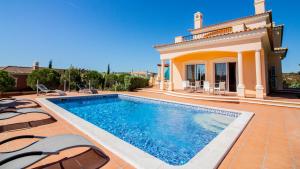 a swimming pool in front of a house at Villas @ Quinta do Vale Golfe in Castro Marim
