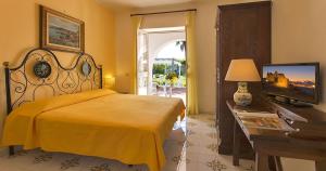 a bedroom with a bed and a television and a table at Hotel Belsole in Ischia +9 photos
