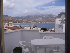 a white table and chairs on a balcony overlooking the water at Mertonas Studios in Karpathos