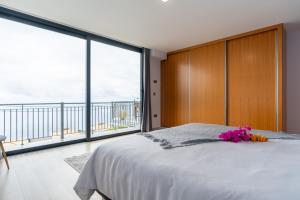 ein Schlafzimmer mit einem großen Bett und einem großen Fenster in der Unterkunft Apartamento Goncalves in Arco da Calheta