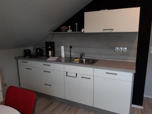 una cocina con armarios blancos y fregadero en Ferienwohnung Trommblick - Natur Pur - Rimbach im Odenwald, en Rimbach