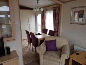 a living room with a table and a chair with a purple pillow at Invernevis in Boat of Garten