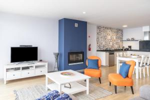 ein Wohnzimmer mit Fernseher und Tisch und Stühlen in der Unterkunft Apartamento Goncalves in Arco da Calheta