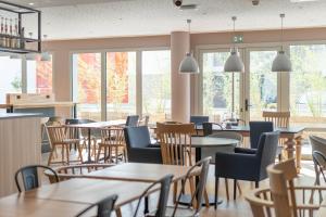 un restaurant avec des tables, des chaises et des fenêtres dans l'établissement Campanile Tours Nord, à Tours
