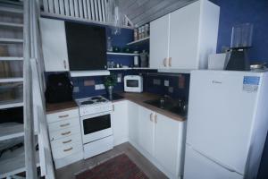 a small kitchen with white cabinets and a refrigerator at Trevlig stuga på landet, centralt 8km från Centrum in Eskilstuna