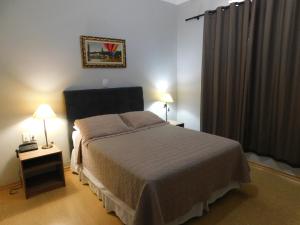 1 dormitorio con 1 cama, 2 lámparas y ventana en Hotel Real São Lourenço, en São Lourenço