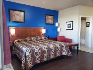a bedroom with a bed and a blue wall at Crossroads Inn & Suites in Victoria