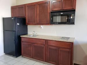 a kitchen with wooden cabinets and a black refrigerator at Crossroads Inn & Suites in Victoria