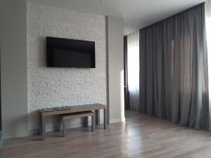 een woonkamer met een tafel en een tv aan de muur bij Atbrīvošanas aleja 80 in Rēzekne
