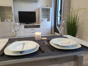 una mesa con dos platos y vasos blancos y una vela en Apartamentos Aranda - Ribera, en Aranda de Duero