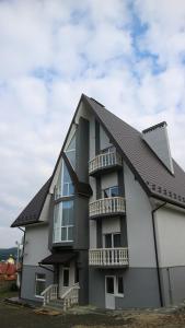 a house with a black roof and a balcony at Вілла MILARO in Skhidnitsa