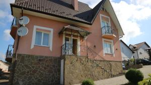 a pink house with a stone wall at Вілла MILARO in Skhidnitsa