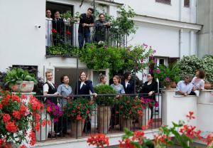 eine Gruppe von Personen, die auf einem Balkon mit Blumen stehen in der Unterkunft Alpi Hotel in Rom