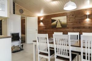 ein Esszimmer mit weißen Stühlen und einer Holzwand in der Unterkunft Villa Haukka in Saariselkä