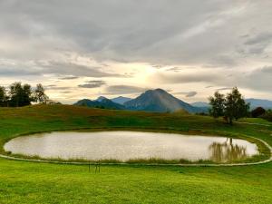 a pond on a golf course with mountains in the background at Il Roccolino in Valsecca +23 photos