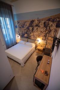 - une chambre avec un lit blanc et un mur en pierre dans l'établissement La Lupa, à Matera