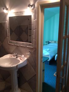 a bathroom with a sink and a mirror and a bed at Pensiunea Vila Dana in Cluj-Napoca