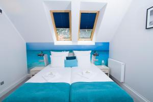 a bedroom with a blue and white bed with two windows at Hudson in Koszalin