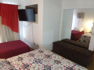 um pequeno quarto com uma cama e um sofá em Pousada Domiciliar Agua Verde em Jaraguá do Sul