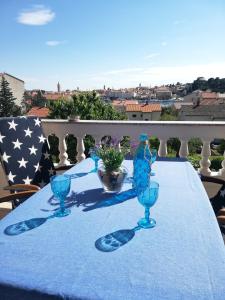 a blue table with two glasses and a bottle on it at Apartmani Paula in Rab
