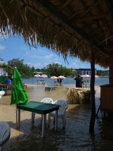 a table with a green umbrella on a beach at Guaraná da Cláudia in Santarém