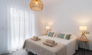 a white bedroom with a bed with towels on it at Sur Suites La Dorada in Fuengirola