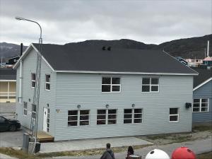 a white house with people standing in front of it at Hotel Nuka in Ilulissat