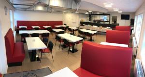 a restaurant with tables and red chairs and a counter at Hotel Nuka in Ilulissat