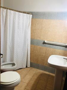 a bathroom with a toilet and a sink at Apart-Hotel Gibert's House in Villa Carlos Paz