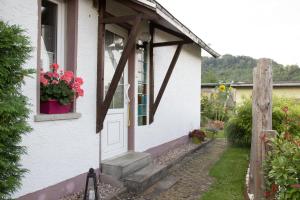 une maison blanche avec une porte blanche et une fenêtre dans l'établissement Kleines Ferienhaus zu Füßen des Rennsteigs, à Ruhla