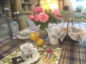 einen Tisch mit einer Vase rosa Rosen und einer Tasse Kaffee in der Unterkunft Ô fil de L'ô in Clairac