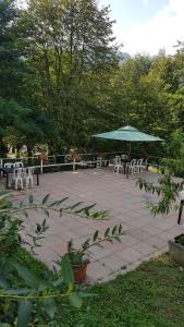 un patio con tavoli, sedie e ombrellone verde di CROTTO CARACO APPARTAMENTI BUNGALOW CHALET a Porlezza