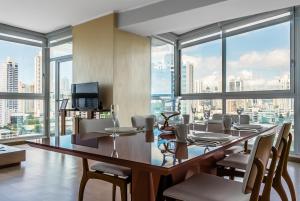 Un comedor con mesa y sillas y ventanas. en Breath-taking Apartment - PH Quartier Del Mar, en Panamá