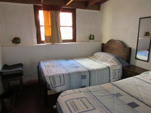 1 dormitorio con 2 camas y 2 ventanas en Hostería Baños Morales en Santiago