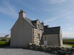 a small stone house with a stone wall at Sineag's Cottage in Pollachar