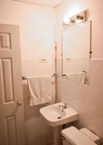 a bathroom with a sink and a toilet and a mirror at Hotel San José de la Montaña in San Salvador