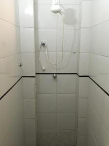 uma casa de banho com um chuveiro com azulejos brancos em hotel Economico da SE em São Paulo