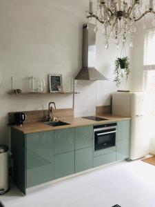 una cocina con armarios verdes y una lámpara de araña en Appartement Zeeuws genoegen, en Vlissingen