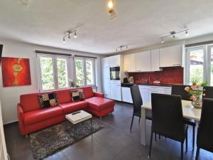 a living room with a red couch and a kitchen at Apartments Steinbock in Leukerbad